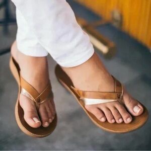 OLUKAI Woman‘s KaeKae Brown and Gold Leather Flip Flops. Size: US 9.